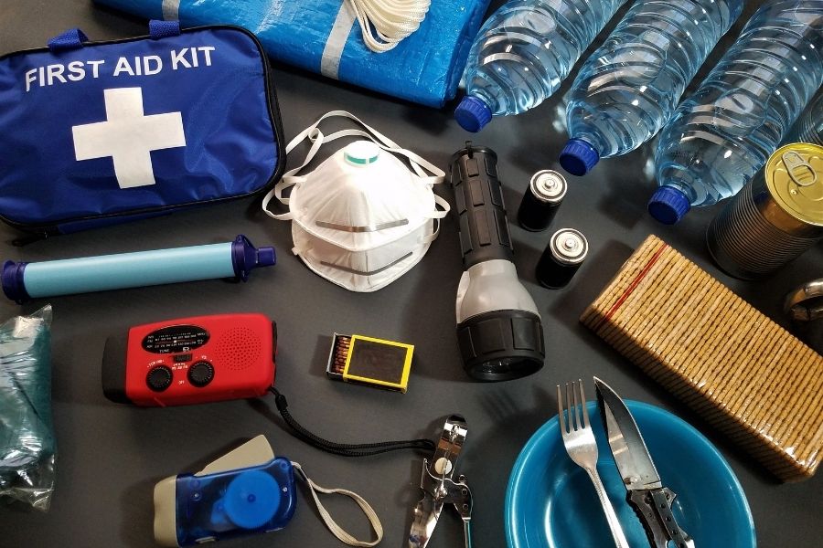first aid kit, water bottles, flash light, mask and other items necessary for surviving an emergency laid flat