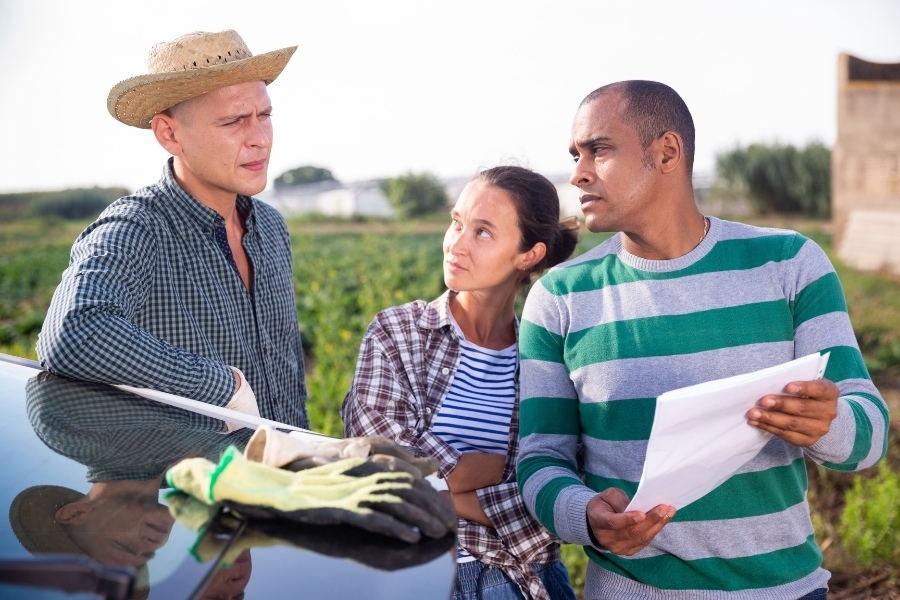 couple holding a piece of paper explaining to farm owner