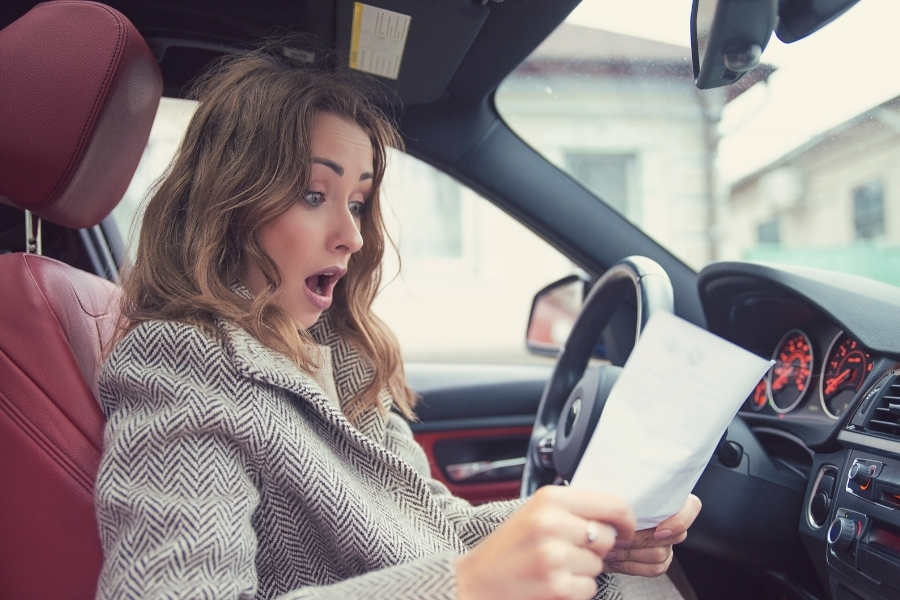 Woman in car shocked looking at a paper