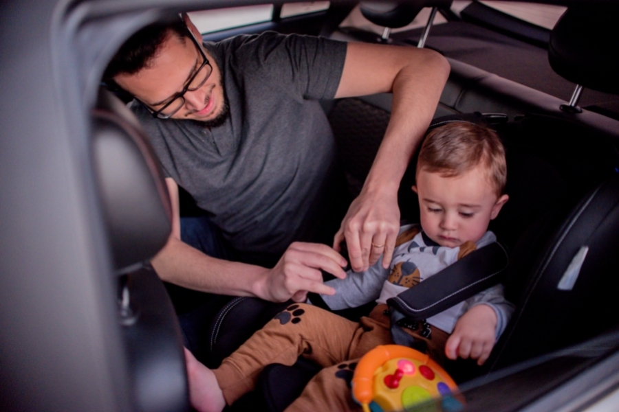 father buckling seatbelt on a car seat with a kid