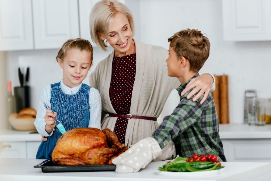 Kids and parent cooking turkey in kitchen